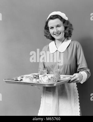 1940s WAITRESS MAID CARRYING TRAY FOOD SERVICE SMILING LOOKING AT CAMERA - h891 HAR001 HARS EYE CONTACT 20-25 YEARS HAPPINESS CHEERFUL CUSTOMER SERVICE 18-19 YEARS SERVANT SMILES JOYFUL SERVER FRIENDLY PLEASANT WAITPERSON YOUNG ADULT WOMAN B&W BLACK AND WHITE CAUCASIAN ETHNICITY LOOKING AT CAMERA OCCUPATIONS OLD FASHIONED PERSONS WAIT STAFF Stock Photo
