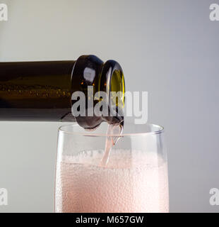 Pink sparkling wine (Champagne) is poured into a glass. Pink foam in the glass. Macro Stock Photo