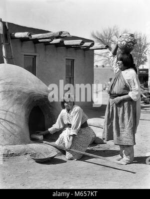 1930s TWO NATIVE AMERICAN WOMEN CARRYING OLLA WATER JAR ON HEAD AND BAKING BREAD IN HORNO OVEN SAN ILDEFONSO PUEBLO NM USA - i1559 HAR001 HARS FRIENDSHIP FULL-LENGTH LADIES INDIANS SPIRITUALITY AMERICANA NOSTALGIA MIDDLE-AGED NORTH AMERICA TOGETHERNESS JAR 25-30 YEARS 45-50 YEARS NORTH AMERICAN MIDDLE-AGED WOMAN AND MUD NATIVE AMERICAN PUEBLO SAN ILDEFONSO MID-ADULT MID-ADULT WOMAN NEW MEXICO YOUNG ADULT WOMAN ADOBE-BUILT B&W BLACK AND WHITE HORNO OVEN INDIGENOUS OLD FASHIONED OLLA OUTDOOR OVEN PERSONS SAN ILDEFONSO SOUTHWEST SOUTHWESTERN Stock Photo