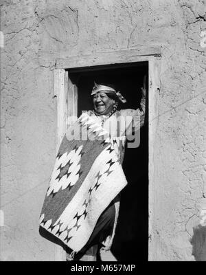 1930s SMILING NATIVE AMERICAN INDIAN MAN STANDING IN DOORWAY WEARING TYPICAL COSTUME SAN ILDEFONSO PUEBLO NEW MEXICO USA - i1651 HAR001 HARS INDIANS NOSTALGIA MIDDLE-AGED MIDDLE-AGED MAN 50-55 YEARS 55-60 YEARS HAPPINESS CHEERFUL SMILES JOYFUL NATIVE AMERICAN PUEBLO MALES NATIVE AMERICANS NEW MEXICO TYPICAL B&W BLACK AND WHITE ILDEFONSO OLD FASHIONED PERSONS Stock Photo