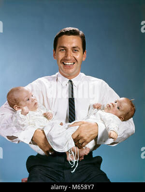 1960s SMILING FATHER LOOKING AT CAMERA HOLDING TWO TWIN BABIES IN ARMS - kb4642 HAR001 HARS IDENTICAL PLEASED JOY LIFESTYLE STUDIO SHOT HEALTHINESS HOME LIFE COPY SPACE HALF-LENGTH CARING INDOORS CONFIDENCE FAMILIES NOSTALGIA FATHERS TOGETHERNESS EYE CONTACT 0-1 YEARS 20-25 YEARS 30-35 YEARS HAPPINESS CHEERFUL DADS PRIDE GROWTH SMILES JOYFUL SMALL GROUP OF PEOPLE BABY BOY 1-6 MONTHS JUVENILES LOOK ALIKE MALES MID-ADULT MID-ADULT MAN YOUNG ADULT MAN CAUCASIAN ETHNICITY IN ARMS LOOKING AT CAMERA OLD FASHIONED PERSONS Stock Photo