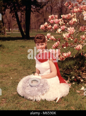 1960s YOUNG WOMAN SITTING BY BLOSSOMING MAGNOLIA TREE WITH SPRINGTIME HAT RED SCARF WHITE GLOVES AND DRESS LOOKING AT CAMERA - kb5215 HAR001 HARS STYLISH SUBURBAN SPRING COLOR OLD TIME FIGURES OLD FASHION 1 JUVENILE STYLE YOUNG ADULT CAUCASIAN PLEASED JOY LIFESTYLE BEAUTIFUL FEMALES GROWNUP HEALTHINESS ONE PERSON ONLY COPY SPACE FULL-LENGTH HALF-LENGTH LADIES INSPIRATION SIT GROWN-UP TEENAGE GIRL SERENITY NOSTALGIA EYE CONTACT 20-25 YEARS BRUNETTE YOUNGSTER HAPPINESS CHEERFUL LEISURE RELAXATION BLOSSOM 18-19 YEARS POSING SMILES JOYFUL TEENAGED HEAD-WARE SOUTHERN BELLE BLOSSOMS JUVENILES Stock Photo