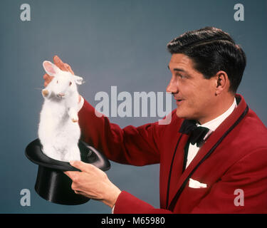 1960s 1970s MAN MAGICIAN WEARING RED SUIT PULLING WHITE RABBIT OUT OF TOP HAT - kc2832 HAR001 HARS JOBS STUDIO SHOT ONE PERSON ONLY COPY SPACE HALF-LENGTH CHARACTER ANIMALS INDOORS PROFESSION ENTERTAINMENT CONFIDENCE NOSTALGIA 30-35 YEARS 35-40 YEARS PERFORMING ARTS ONE ANIMAL MAGICIANS PEOPLE STORY SKILL OCCUPATION ILLUSION SKILLS PERFORMER CAREERS CHARACTERS EXCITEMENT ENTERTAINER ACTORS PERFORMERS ENTERTAINERS HEAD-WARE MAGICAL WHITE RABBIT CREATURE LEGERDEMAIN MALES MAMMAL MID-ADULT MID-ADULT MAN RODENT TOP HAT CAUCASIAN ETHNICITY OCCUPATIONS OLD FASHIONED PERSONS PRESTIDIGITATION Stock Photo