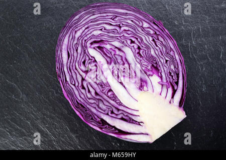 Red cabbage, cut through, on a grey slate board. Stock Photo
