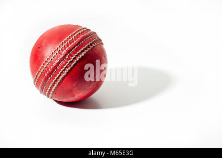 Red cricket ball on a white background in strong side lighting Stock Photo