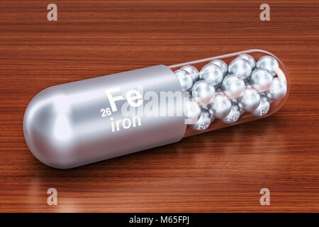 Capsule with iron Fe element on the wooden table. 3D rendering Stock Photo