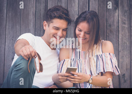 Beautiful couple in love sharing smart phone to watch media content outdoors Stock Photo