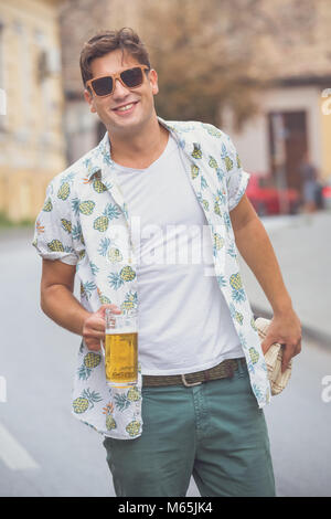 Portrait of handsome modern hipster man walking on the city street with beer stein Stock Photo