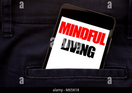 Word, writing Mindful Living. Business concept for Life Happy Awareness Written phone mobile phone, cellphone placed in man front jeans pocket. Stock Photo