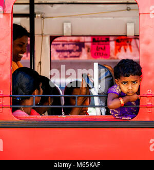 A young boy looking out curiously from a local bus in Munnar, in Kerala, India. Stock Photo