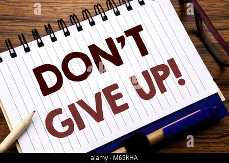 Hand writing text caption inspiration showing Don t Give Up. Business concept for Motivation Determination, Written on notebook paper, wooden backgrou Stock Photo