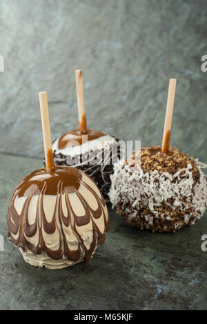 Caramel apples with chocolate, coconut, nuts, cookie crumbs sitting on a piece of slate Stock Photo