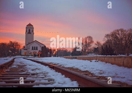 sunrise photo of the boise train depot and the railroad tracks covered in snow with a flock of geese flying in the morning light on a cold winter day  Stock Photo