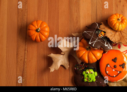 Funny halloween gingerbread cookies and pumpkin on wooden table Stock Photo