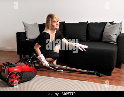 House cleaning, woman vacuuming couch in house Stock Photo