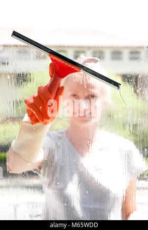 Cleaning woman washing windows using a squeegee to wash a window Stock Photo