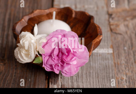 Spa, wellness or body care concept. Flowers in wooden bowl on table Stock Photo