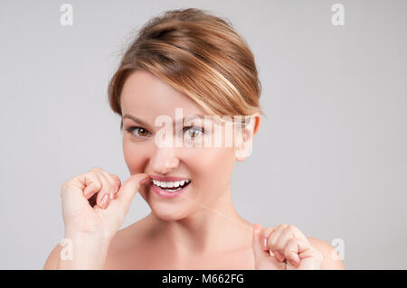 Close up portrait of beautiful woman cleaning teeth with dental floss Stock Photo