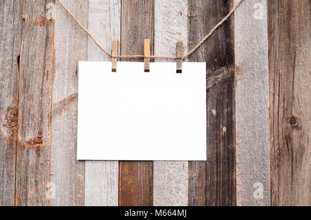 Clothespin hanging with blank paper on wooden background texture Stock Photo