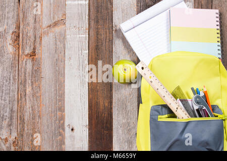 School supplies in backpack on wooden background. Back to school Stock Photo