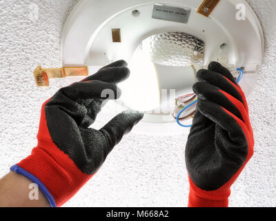 Electrician technician screws the low consumption led light bulb into a residential electrical system Stock Photo