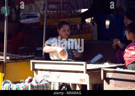 An indigenous, ethnic K'iche' Maya woman makes tortillas for sale in the market place. Santa Cruz del Quiché, Guatemala. Stock Photo