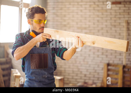 carpenter testing wood plank evenness at workshop Stock Photo