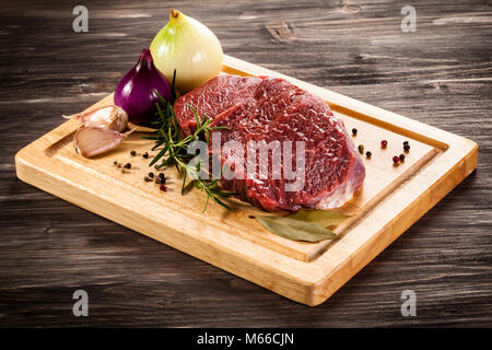 Raw beef on cutting board on wooden table Stock Photo
