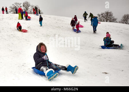 Skipton, North Yorkshire / UK - February 28th 2018: A girl slides down a snow covered hill on a sledge after snow fall across the UK Stock Photo