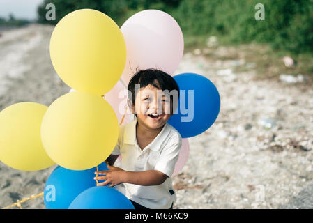 young asian boy smiling and laughing while holding a balloons. family concept Stock Photo