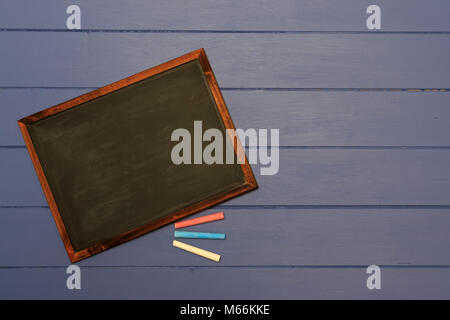 Slate chalk board with coloured chalk sticks on shabby blue board background Stock Photo