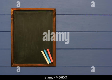 Slate chalk board with coloured chalk sticks on shabby blue board background Stock Photo