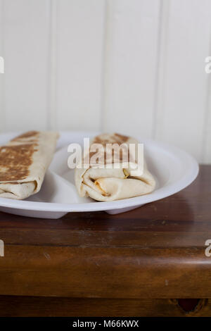 A pair of warm, toasted burritos served on a divided plate Stock Photo