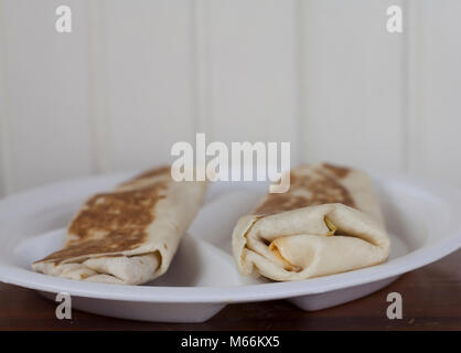 A pair of warm, toasted burritos served on a divided plate Stock Photo