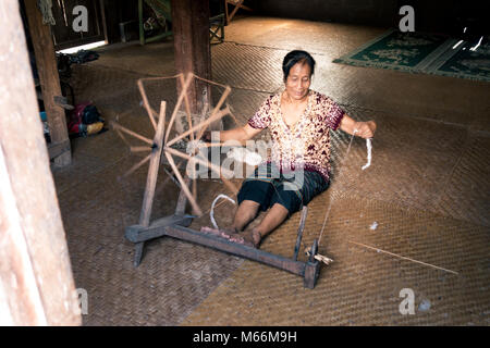 An ethnic elderly woman spinning yarn in a small tribal village just off of the Nam Ou river in Laos. Stock Photo