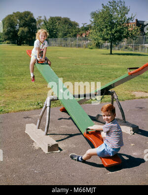 1960s BOY GIRL PLAYGROUND SITTING ON SEESAW SEE-SAW TEETER-TOTTER - kj1915 HAR001 HARS HAPPINESS ADVENTURE EXCITEMENT RECREATION GROWTH SIBLING COOPERATION JUVENILES MALES CAUCASIAN ETHNICITY LOOKING AT CAMERA OLD FASHIONED PLAYMATES SEE-SAW TEETER-TOTTER Stock Photo
