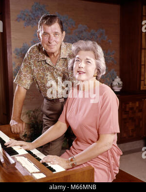 1960S SMILING SENIOR COUPLE TOGETHER AT ELECTRIC HOME ORGAN HUSBAND LOOKING AT CAMERA STANDING BEHIND WIFE WHO IS PLAYING - km1747 HAR001 HARS CAUCASIAN LIFESTYLE SOUND ELDER FEMALES MARRIED ORGAN SPOUSE HUSBANDS GROWNUP HEALTHINESS HOME LIFE COMMUNICATING COPY SPACE FRIENDSHIP HALF-LENGTH LADIES GROWN-UP COUPLES INDOORS ENTERTAINMENT SENIOR MAN SENIOR ADULT NOSTALGIA MIDDLE-AGED TOGETHERNESS EYE CONTACT SENIOR WOMAN 55-60 YEARS 60-65 YEARS PERFORMING WIVES HAPPINESS OLDSTERS OLDSTER LEISURE STYLES ENJOYING ELDERS CONNECTION FASHIONS COOPERATION COMMUNICATE HARMONY MALES CAUCASIAN ETHNICITY Stock Photo