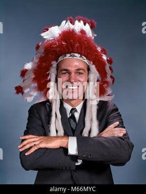 1960s SMILING MAN WEARING SUIT AND TIE AND NATIVE AMERICAN INDIAN FEATHER HEADDRESS ARMS FOLDED LOOKING AT CAMERA - kp727 HAR001 HARS STUDIO SHOT ONE PERSON ONLY UNITED STATES COPY SPACE HALF-LENGTH INDIANS UNITED STATES OF AMERICA INDOORS CONFIDENCE NOSTALGIA EYE CONTACT 25-30 YEARS 30-35 YEARS 35-40 YEARS SUCCESS SINGLE OBJECT HAPPINESS STRENGTH VICTORY STRATEGY AND CHIEF EXCITEMENT LEADERSHIP POWERFUL PRIDE AUTHORITY CEO SMILES JOYFUL CONCEPTUAL COOPERATION HEADDRESS NATIVE AMERICAN MALES MID-ADULT MID-ADULT MAN BIGWIG CAUCASIAN ETHNICITY CHIEF EXECUTIVE LOOKING AT CAMERA OCCUPATIONS