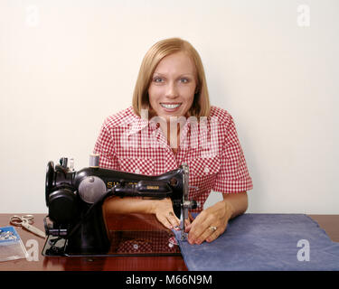 1970s SMILING BLOND WOMAN HOUSEWIFE LOOKING AT CAMERA OPERATING ANTIQUE BLACK SINGER SEWING MACHINE - ks13624 HAR001 HARS GROWNUP ONE PERSON ONLY HOME LIFE COPY SPACE LADIES GROWN-UP INDOORS CRAFT CONFIDENCE SEW NOSTALGIA EYE CONTACT 25-30 YEARS 30-35 YEARS HOMEMAKER SINGLE OBJECT SKILL HAPPINESS HOMEMAKERS OPERATING HEAD AND SHOULDERS CHEERFUL HOUSEWIVES SMILES JOYFUL CREATIVITY SEAMSTRESS CHECKERED CRAFTING MID-ADULT MID-ADULT WOMAN PEOPLE ADULTS PRECISION CAUCASIAN ETHNICITY LOOKING AT CAMERA OCCUPATIONS OLD FASHIONED PERSONS RED AND WHITE Stock Photo
