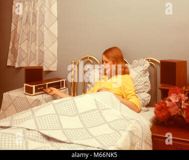 1970s SMILING REDHEADED WOMAN LYING IN BED SETTING ALARM CLOCK RADIO TO WAKE UP IN THE MORNING - kt2599 BAN001 HARS FEMALES GROWNUP HEALTHINESS ONE PERSON ONLY HOME LIFE COMMUNICATING PREPARING COPY SPACE HALF-LENGTH LADIES PHYSICAL FITNESS GROWN-UP INDOORS ENTERTAINMENT NOSTALGIA MORNING RESTING LINEN 20-25 YEARS HEAD AND SHOULDERS CHEERFUL 18-19 YEARS SMILES JOYFUL ELECTRIC APPLIANCE RED HAIR COMMUNICATE RESTFUL COMMUNICATIONS REDHEADED REST YOUNG ADULT WOMAN ABOUT TO CAUCASIAN ETHNICITY GOING TO SLEEP GOOD NIGHT OLD FASHIONED PERSONS Stock Photo