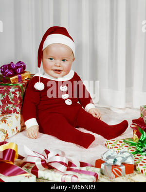 1960s HAPPY BABY WEARING SANTA CLAUS FOOTED PAJAMAS SITTING AMONG WRAPPED CHRISTMAS PRESENTS - kx3618 HAR001 HARS HOME LIFE COPY SPACE FULL-LENGTH PAJAMAS INDOORS NOSTALGIA HAPPINESS CHEERFUL SANTA CLAUS SMILES DECEMBER JOYFUL COOPERATION DECEMBER 25 ST. NICK BABY BOY 6-12 MONTHS JOLLY JUVENILES MALES CAUCASIAN ETHNICITY FOOTED OLD FASHIONED SANTA SUIT Stock Photo