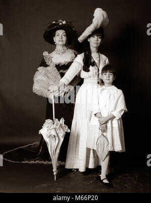 1960s THREE GENERATIONS WOMEN GRANDMOTHER MOTHER DAUGHTER POSED STANDING LOOKING AT CAMERA WEARING 1890s FASHION DRESSES - o3311 HAR001 HARS STUDIO SHOT GROWNUP FULL-LENGTH GROWN-UP CHARACTER 1900s INDOORS CONFIDENCE FAMILIES NOSTALGIA TOGETHERNESS EYE CONTACT 25-30 YEARS 30-35 YEARS 40-45 YEARS 45-50 YEARS 7-9 YEARS MATERNAL YOUNGSTER PARENTHOOD TRIO PARENTAL PRIDE 1890s MOTHERHOOD GRANDCHILD SMALL GROUP OF PEOPLE JUVENILES MID-ADULT MID-ADULT WOMAN B&W BLACK AND WHITE CAUCASIAN ETHNICITY OLD FASHIONED PERSONS Stock Photo