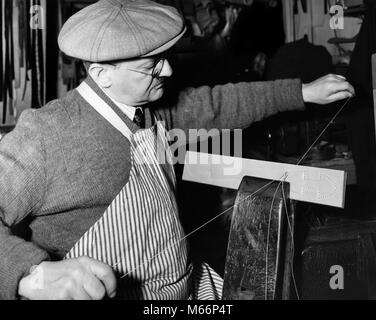 1920s 1930s TRADITIONAL CRAFTSMAN WEARING CAP SWEATER APRON AND GLASSES SEWING LEATHER LUGGAGE HANDLE WITH THREAD - q37468 CPC001 HARS HALF-LENGTH TRADITIONAL GROWN-UP INDOORS PROFESSION CRAFT SEW NOSTALGIA MIDDLE-AGED MAN 40-45 YEARS 45-50 YEARS NEEDLES THREAD SKILL OCCUPATION MANUAL CAREERS KNOWLEDGE PRIDE AUTHORITY MANUFACTURING CREATIVITY SKILLED TRADE CRAFTSMAN CRAFTSMEN FINE MALES PRECISION ARTISAN B&W BLACK AND WHITE CAUCASIAN ETHNICITY HANDICRAFT HANDLES LEATHER CRAFT OCCUPATIONS OLD FASHIONED PERSONS VISE Stock Photo