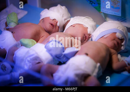 Newborn triplets baby are under the device with ultraviolet radiation in the maternity hospital Stock Photo