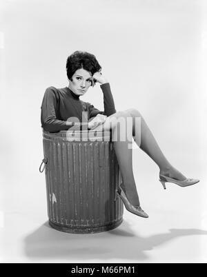 1960s SAD SERIOUS WORRIED EXPRESSION BRUNETTE WOMAN SITTING IN METAL TRASH CAN LEGS OVER SIDE IN A JAM LOOKING AT CAMERA - s16823 HAR001 HARS ONE PERSON ONLY COMMUNICATING FULL-LENGTH LADIES SIT CANS GROWN-UP CHARACTER INDOORS NOSTALGIA CONTEMPLATING EYE CONTACT 20-25 YEARS BRUNETTE JAM FIRED YOUNGSTER DISASTER HUMOROUS TRASH THINK 18-19 YEARS PONDER PONDERING COMMUNICATE CONTEMPLATIVE EMPLOYEE CONTEMPLATE PEOPLE ADULTS SITUATION YOUNG ADULT WOMAN B&W BLACK AND WHITE CAUCASIAN ETHNICITY EX-EMPLOYEE LET GO LOOKING AT CAMERA OCCUPATIONS OLD FASHIONED OUT OF WORK PERSONS PREDICAMENT REDUNDANT Stock Photo