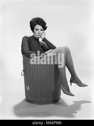 1960s UNHAPPY SAD DEPRESSED WOMAN IN TRASH CAN WEARING HIGH HEELS LOOKING AT CAMERA - s16824 HAR001 HARS GROWN-UP CHARACTER THROW INDOORS NOSTALGIA SADNESS CANNED GARBAGE EYE CONTACT 20-25 YEARS 25-30 YEARS SELF FIRED TRASH IMAGE VALUE EMPLOYEE DISCARDED PEOPLE ADULTS THROWN WORTH YOUNG ADULT WOMAN B&W BLACK AND WHITE CAUCASIAN ETHNICITY DUMPED EX-EMPLOYEE IDLE LAID OFF LET GO LOOKING AT CAMERA MENTAL ILLNESS OLD FASHIONED OUT OF WORK PERSONS REDUNDANT SELF IMAGE THROW AWAY TRASH CAN UNEMPLOYED WORTHLESS Stock Photo