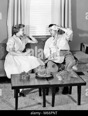 1950s COUPLE SITTING ON LIVING ROOM COUCH TRYING TO COOL DOWN DRINKING ICED DRINK BEFORE FAN ON COFFEE TABLE - s5601 HAR001 HARS COPY SPACE FULL-LENGTH LADIES FAN COUPLES INDOORS SWEAT ICED NOSTALGIA SWEATING SUMMERTIME 30-35 YEARS 35-40 YEARS BEFORE TEMPERATURE WIVES LIVING ROOM TRYING UNCOMFORTABLE SOLUTIONS COOL DOWN MALES MID-ADULT MID-ADULT MAN MID-ADULT WOMAN B&W BLACK AND WHITE CAUCASIAN ETHNICITY COFFEE TABLE HEAT WAVE HUMID OLD FASHIONED OPPRESSIVE OVER HEATED OVERHEATED PERSONS PERSPIRING SWELTERING WIPING FACE Stock Photo