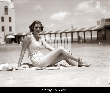 1930s WOMAN SITTING POOL SIDE LOOKING AT CAMERA WEARING FASHIONABLE SUNGLASSES BATHING SUIT AND SANDALS MIAMI BEACH FLORIDA USA - s9100 HAR001 HARS STYLE TROPICAL BATHING YOUNG ADULT VACATION CAUCASIAN WEAR LIFESTYLE FEMALES SWIM GROWNUP ONE PERSON ONLY UNITED STATES COPY SPACE FULL-LENGTH LADIES GROWN-UP UNITED STATES OF AMERICA NOSTALGIA NORTH AMERICA EYE CONTACT NORTH AMERICAN OCCUPATION URBAN CENTER SWIMMING POOL LEISURE RELAXATION RECREATION WATER RECREATION SOUTHEAST OCCASION POSING SOUTHERN EAST COAST SANDY POOL SIDE GULF COAST SWIM WEAR FL MODELING POOL-SIDE SANDALS YOUNG ADULT WOMAN Stock Photo