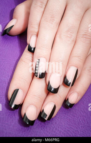 Female hands with black manicure on the violet background Stock Photo