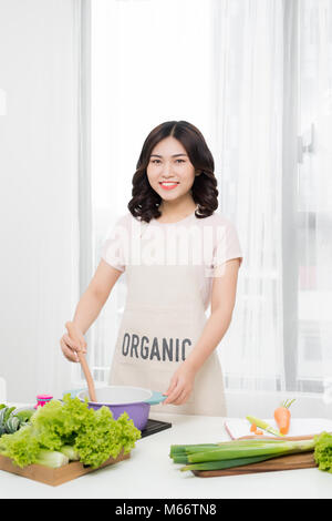 Healthy food. Asian woman cooking in the kitchen with wooden spoon Stock Photo